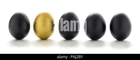 Un uovo dorato nero tra le uova in una riga isolata su sfondo bianco - la concezione di business Foto Stock