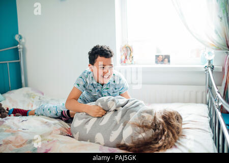 Little Boy e sua sorella sono playfighting su un letto di casa. Foto Stock