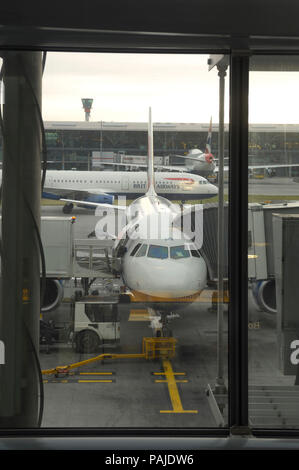 British Airways Airbus A319-100 e Boeing 747-400 parcheggiata con un320 rullaggio dietro al terminale5 con jetway attaccata Foto Stock