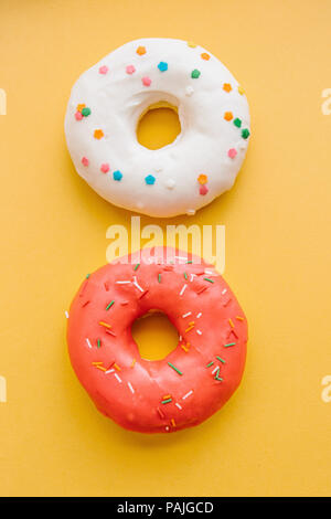 Bianco e rosa ciambella giacciono su uno sfondo giallo Foto Stock