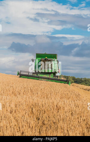 Agricoltura del Regno Unito, John Deere mietitrebbia Hillmaster durante il lavoro su un inverno di raccolto di orzo, con spazio di copia Foto Stock