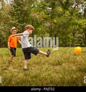 Due graziosi bimbi piccoli, giocando a calcio insieme, per la stagione estiva. I bambini giocano a calcio per esterno Foto Stock