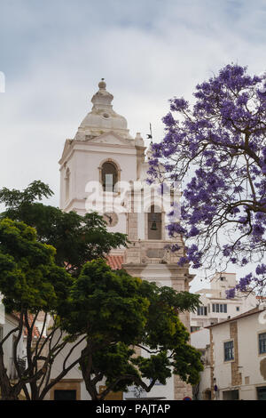 Igreja de Santo Antonio - San Antonio chiesa in portoghese di Lagos. Alberi con fresche foglie verdi e un altro con fiori viola in primo piano. C Foto Stock