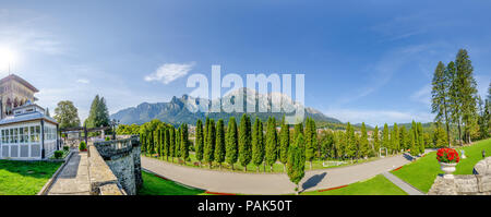 Cantacuzino Castello e le montagne dei Carpazi con il Caraiman picco in un ultrawide vista panoramica su una soleggiata giornata estiva con la città di Busteni su t Foto Stock