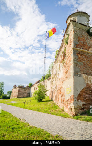 La fortezza medievale di Brasov con la bandiera rumena e alte pareti di mattoni Foto Stock