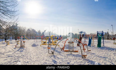 Parco giochi per bambini su una soleggiata giornata invernale con il bianco della neve e una sensazione di freddo Foto Stock