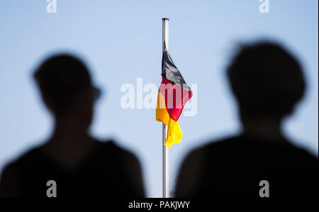 Warendorf, Germania. Il 24 luglio, 2018. Le sagome delle persone in lutto può essere visto nella parte anteriore di una bandiera tedesca al memoriale di servizio per Hans Guenter Winkler. Winkler era morto in Warendorf il 9 luglio 2018. Credito: Friso Gentsch/dpa/Alamy Live News Foto Stock