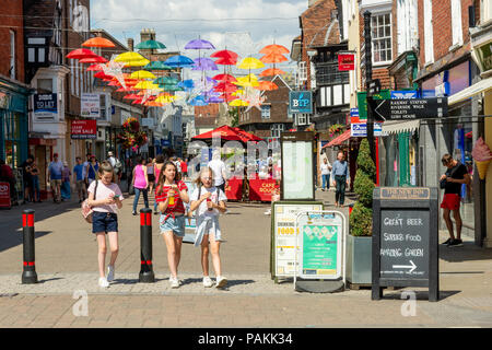 Salisbury, Wiltshire, Regno Unito, 24th luglio 2018, Meteo: Caldo e soleggiato nella città cattedrale con temperature che si aggirano verso i 30 gradi. Un colorato ombrello arte installazione proietta un po 'di ombra su High Street. Foto Stock