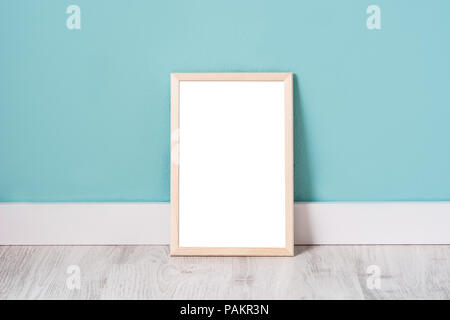 Telaio mockup su bianco con pavimento in legno e muro color turchese. Copyspace. Foto Stock