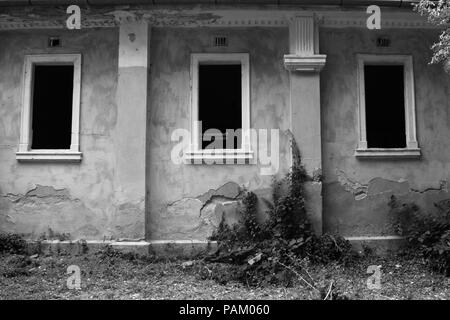 Tre finestre in un edificio abbandonato in bianco e nero Foto Stock