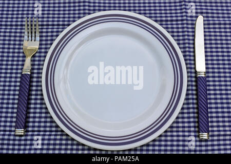 Bianco e blu con piastra di posate su un blu tovaglia gingham. Fare picnic o messa in tavola. Foto Stock