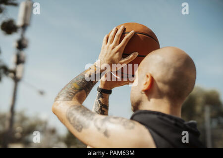 Close up calvo uomo attraente giocare a basket sul campo da basket. Foto Stock