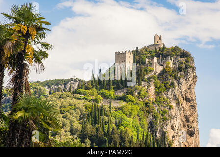 Il castello in rovina di Arco che siede su uno sperone roccioso sopra il fiume Sarca, in Trentino, regione dell'Italia, in bright sole primaverile Foto Stock