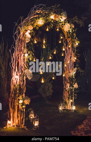 Di notte la cerimonia di nozze, arco sulla parte decorato con luci e candele in tondo le sfere di vetro Foto Stock