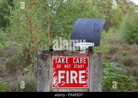 Non avviare il segno di fuoco e un incendio di battitore con alberi e piante della campagna in background Foto Stock