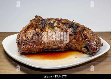 Grigliata di tri punta a fette di bistecca su una piastra bianca sul tavolo della cucina Foto Stock