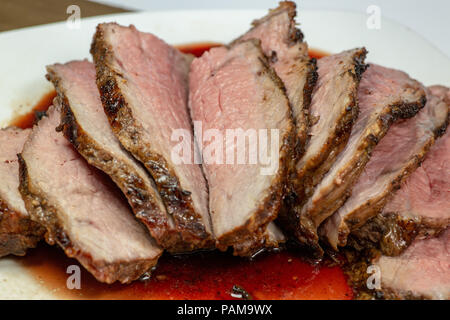 Grigliata di tri punta a fette di bistecca su una piastra bianca sul tavolo della cucina Foto Stock