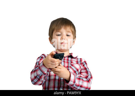 Un ragazzino che tiene un telecomando. Egli appare come egli è veramente incentrato su quale pulsante da premere. Egli è in possesso la sua bocca solo a destra. Vi è un cl Foto Stock