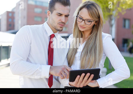 Grave manager mostra i dati finanziari sui tablet ad un collega collega Foto Stock