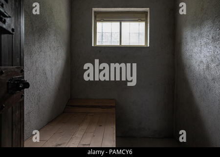Piccolo carcere cella di cemento con una piccola finestra e un pallet di legno. Foto Stock