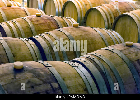 Vecchio e colorate in legno barili di vino in righe all'interno di una cantina di vini Foto Stock