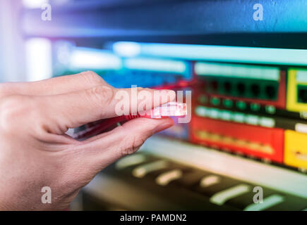 Mano collegando il cavo nel commutatore di rete Foto Stock