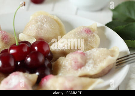 Vareniki (pierogi) con ciliegie su un bianco sullo sfondo di legno - Ucraina piatto nazionale Foto Stock