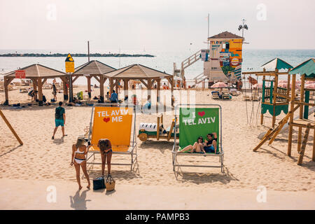 Beachgoers rilassarsi nelle sedie e sulla sabbia al colorato Frishman spiaggia di Tel Aviv, Israele Foto Stock