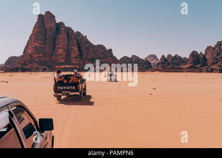 Trucchi del raccoglitore pieno di turisti drive in un convoglio attraverso il deserto rosso sands nel famoso Wadi Rum National Park, Giordania Foto Stock