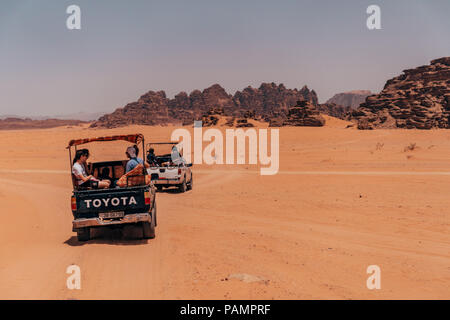 Trucchi del raccoglitore pieno di turisti drive in un convoglio attraverso il deserto rosso sands nel famoso Wadi Rum National Park, Giordania Foto Stock