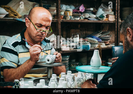 Due palestinesi vasai danno una mano di vernice decorativa per alcuni argilla bianca porcellana Foto Stock