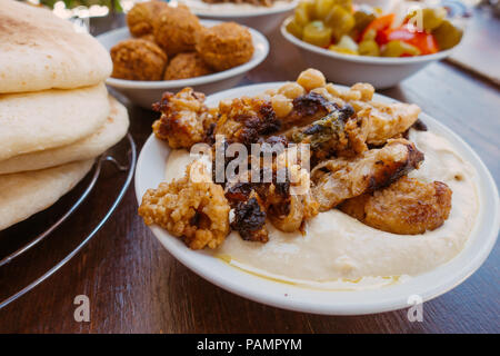 Una ciotola di fresco hummus con cavolfiore alla griglia e pane pita, falafel e sottaceti in un ristorante a Gerusalemme, Israele Foto Stock