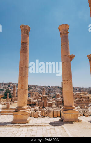 Due antiche colonne greco-romana stand tall all'entrata di un vecchio palazzo di Jerash, Giordania Foto Stock