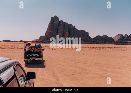 Trucchi del raccoglitore pieno di turisti drive in un convoglio attraverso il deserto rosso sands nel famoso Wadi Rum National Park, Giordania Foto Stock