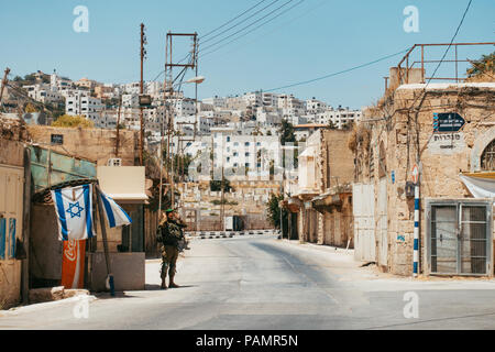 Un soldato delle Forze di Difesa Israeliane sta di guardia per impedire qualsiasi musulmani di entrare in un quartiere abitato a Hebron, Cisgiordania, Israele Foto Stock