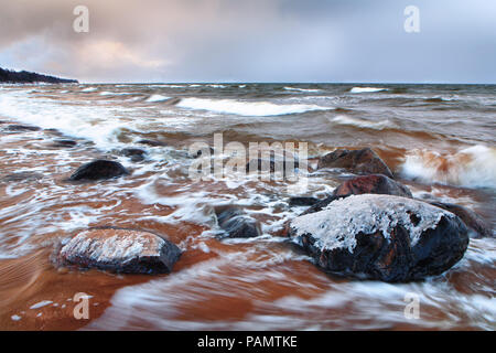 Autunno tempesta nel Mar Baltico con sabbia rossa e il ghiaccio sulle rocce Foto Stock