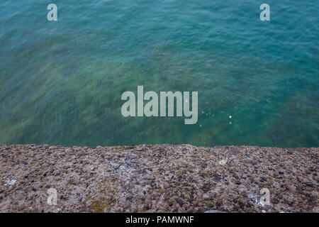 Vista del mare blu in basso dal vecchio muro di pietra. Sullo sfondo del mare Foto Stock