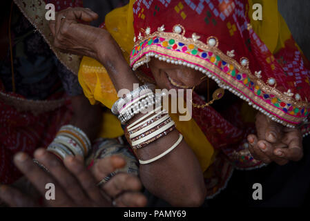 Donna indiana sorridente, indossando un dorato anello di naso, un rosso e senape foulard ricamati e molti braccialetti. 4 mani nel telaio. Foto Stock