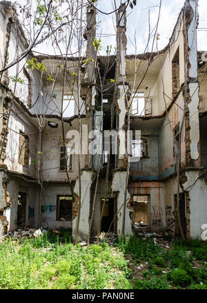 Le rovine e ricoperta di vegetazione la facciata interna di un vecchio edificio storico, danneggiate e distrutte durante la guerra civile a Beirut, Libano Foto Stock