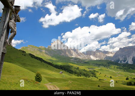 Puez Odle mountain vista dal sentiero vicino Raiser Pass con una scultura in legno raffigurante Gesù Cristo sulla croce, Val Gardena, Dolomiti, Italia Foto Stock