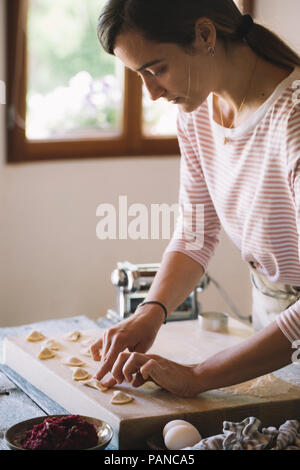 Donna preparare ravioli, barbabietole di riempimento di salvia Foto Stock