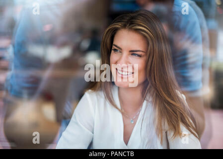 Ritratto di felice giovane donna dietro il vetro di finestra Foto Stock