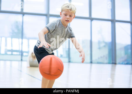 Scolaro giocare a basket in palestra classe Foto Stock