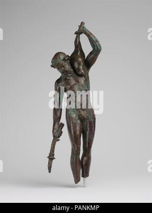 Statuetta in bronzo di satiro con una torcia e otre. Cultura: greco. Dimensioni: H. 9 15/16 in. (25,3 cm). Data: 3rd-2nd secolo A.C. Thiasoi erano giubilanti celebrazioni in onore di Dioniso che erano frequentate da satiri e menadi. Dalla letteratura antica, apprendiamo che si è verificato thiasoi all'aperto, e spesso di notte. Questa bella satiro di bronzo può essere identificato come un partecipante in un tale revel. Un aspetto insolito della sua iconografia è la torcia invertita, un motivo con grande potenziale narrativo, per il satiro può essere lo spegnimento o forse di illuminazione è da un focolare. La piena otre implica Foto Stock