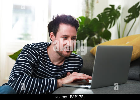 Uomo seduto a casa, utilizzando laptop