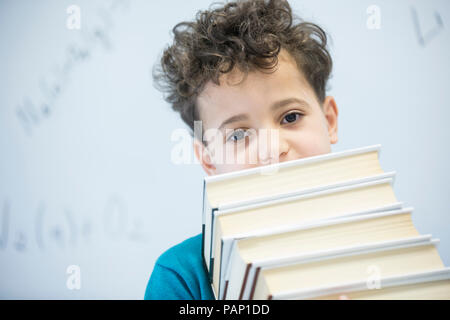 Ritratto di scolaro il trasporto di libri in classe Foto Stock