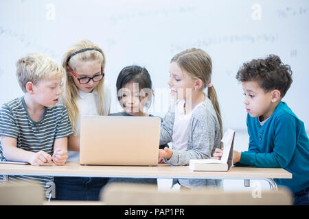 Gli alunni con laptop apprendimento insieme in classe Foto Stock