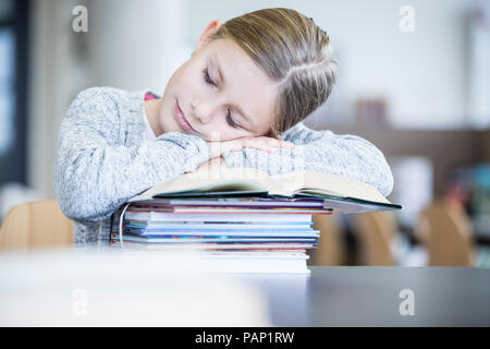 Da studentessa di dormire sulla pila di libri sul tavolo a scuola Foto Stock