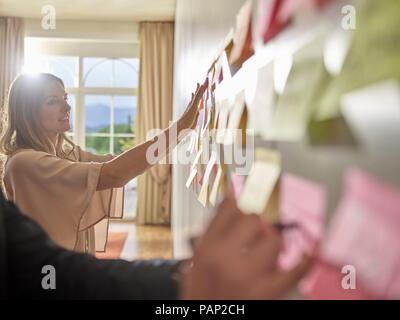 I colleghi a raccogliere idee su dei foglietti in corrispondenza della parete Foto Stock