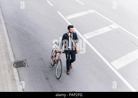 Imprenditore con bicicletta e telefono cellulare a camminare sulla strada Foto Stock